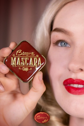 Woman wearing cruelty-free Bésame red lipstick holding a Cake Mascara container