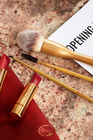 Bésame's red lipstick and lipstick and makeup brushes on marble surface
